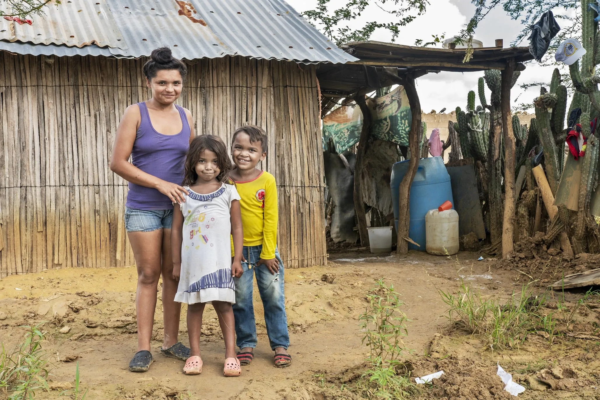 Pedro stands with his family in front of his home in Colombia.