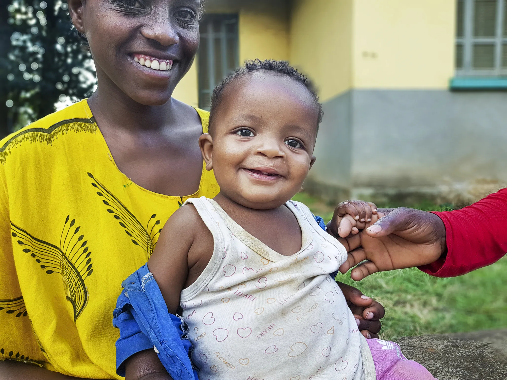 Tesfasihu sits with her 2-year-old son, Ashenafi, as he holds his father’s finger.