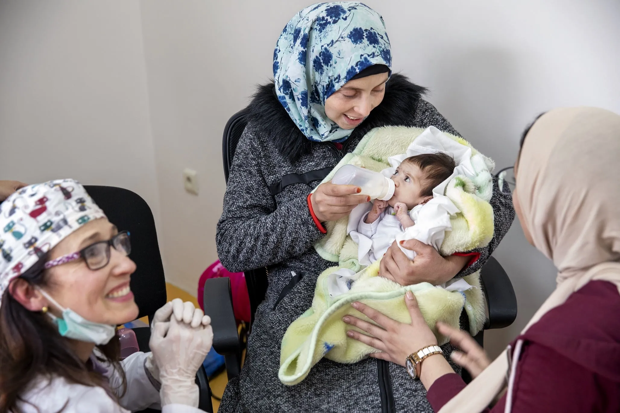 Volunteer dentist Dr. Teresita Pannaci of Venezuela, left, observes as Janat is fed by her mom while testing out her new feeding plate.