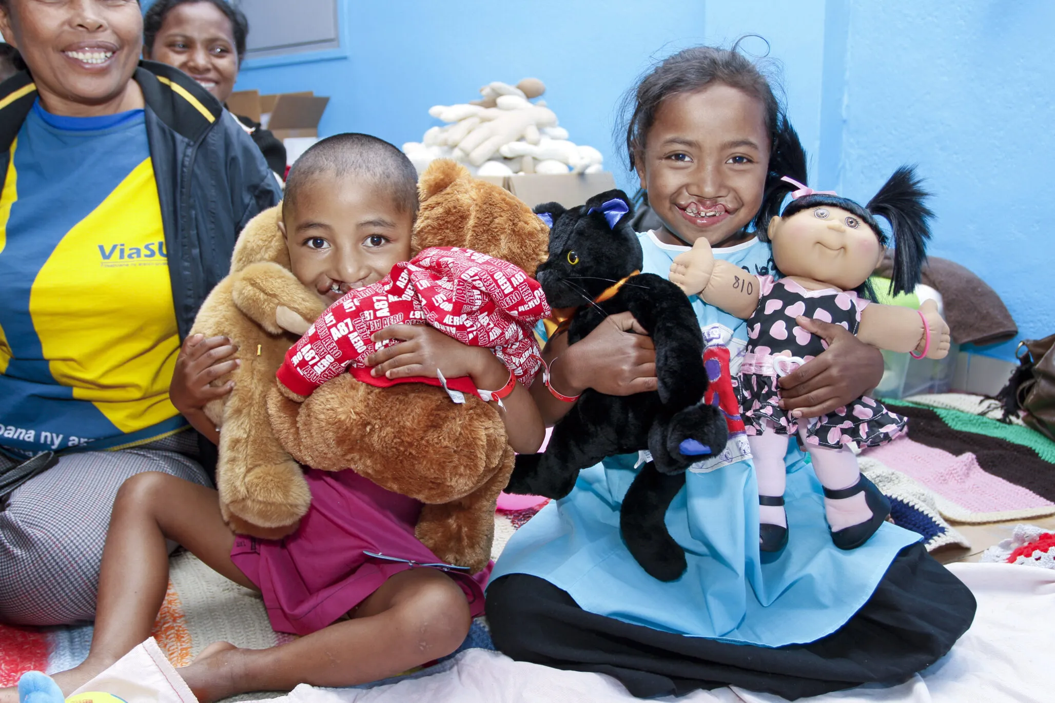 During a 2011 surgical program in Madagascar, 4-year-old Clarra, left, and 8-year-old Vololoniana, right, play with teddy bears in child life as they wait for surgery.