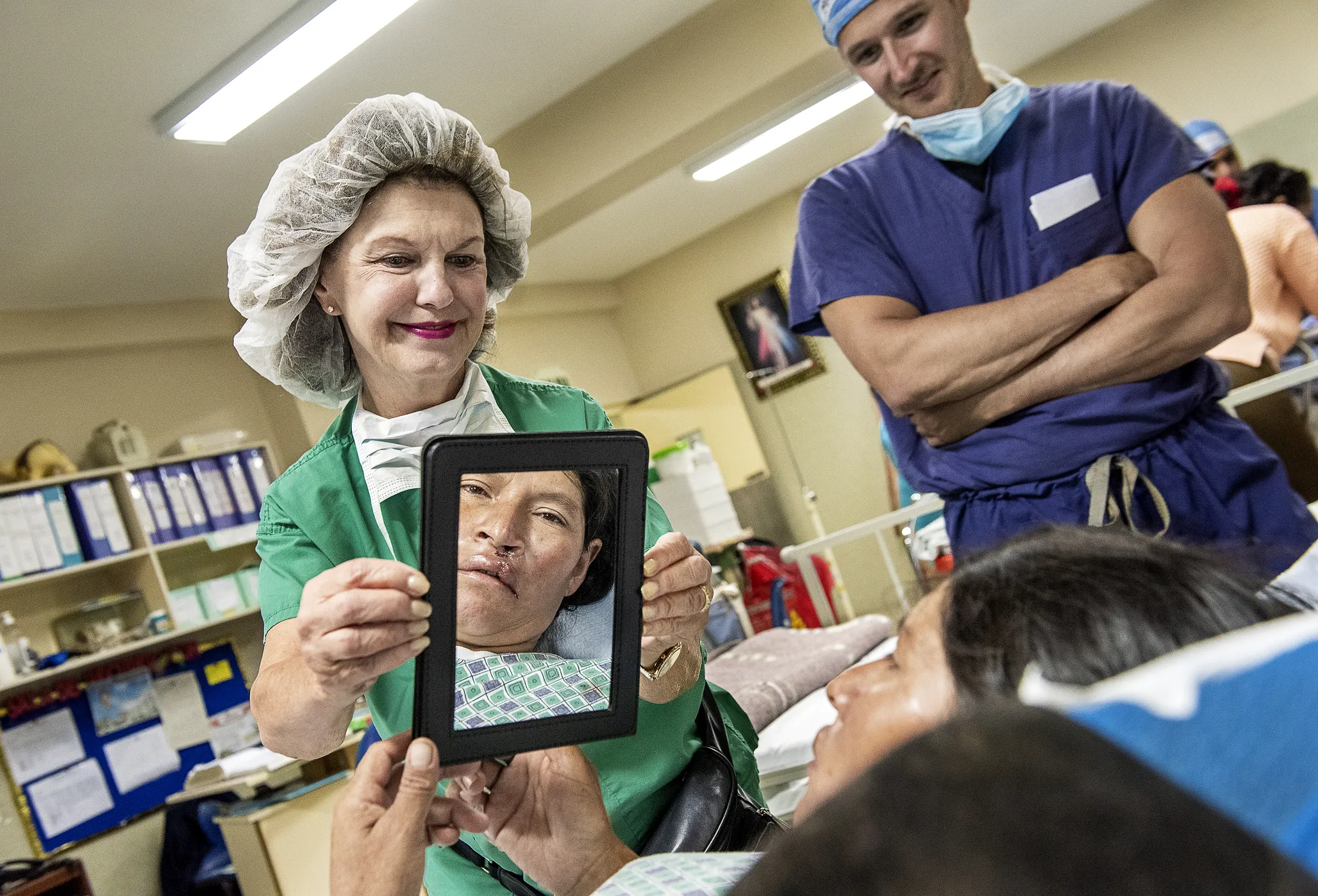 Clinical coordinator Linda Highfield of the U.S. holds a mirror for Andrea to see her new smile after receiving surgery to repair her cleft lip.