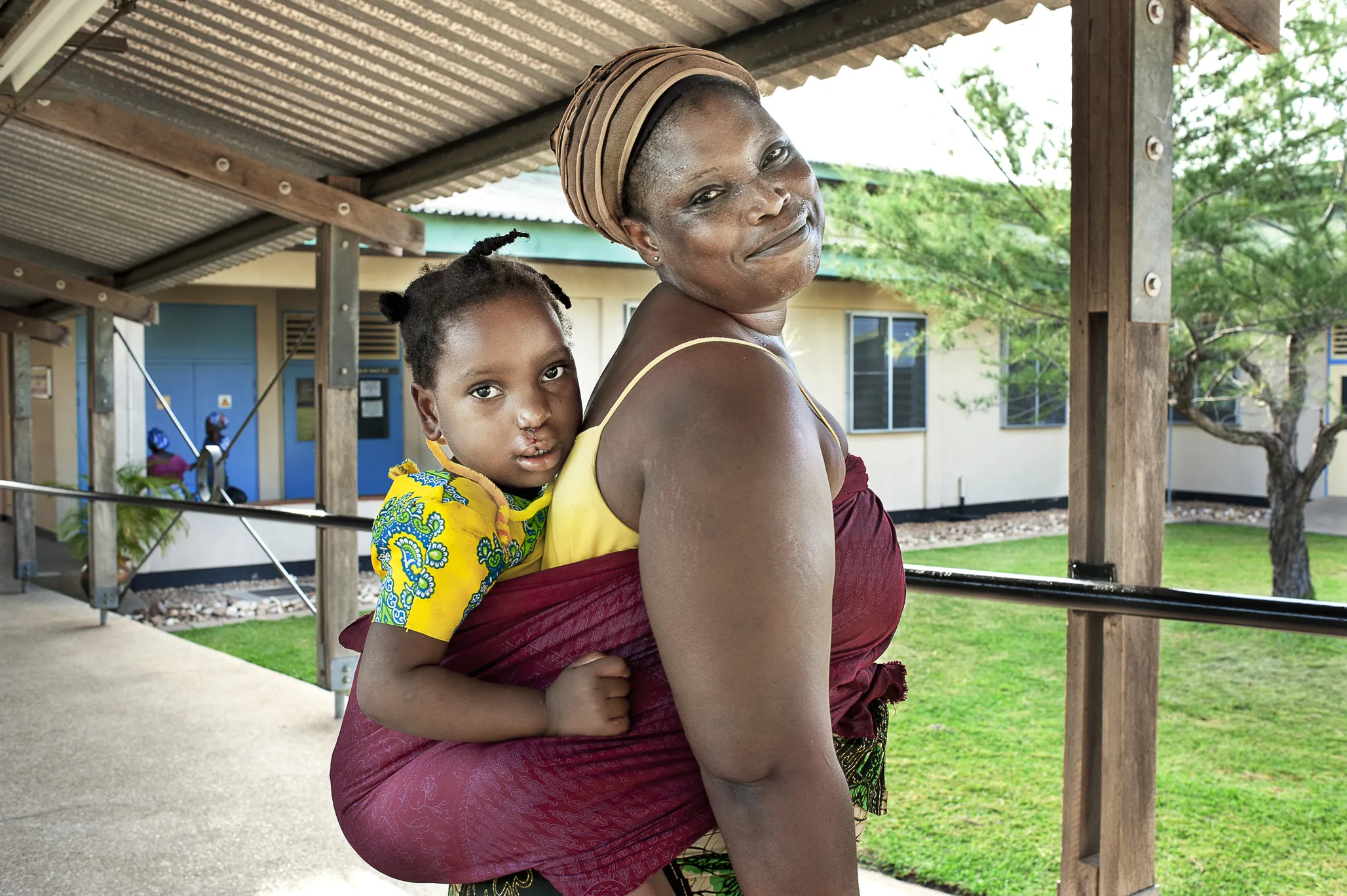 Mariana carries her daughter, Ramata, after surgery.