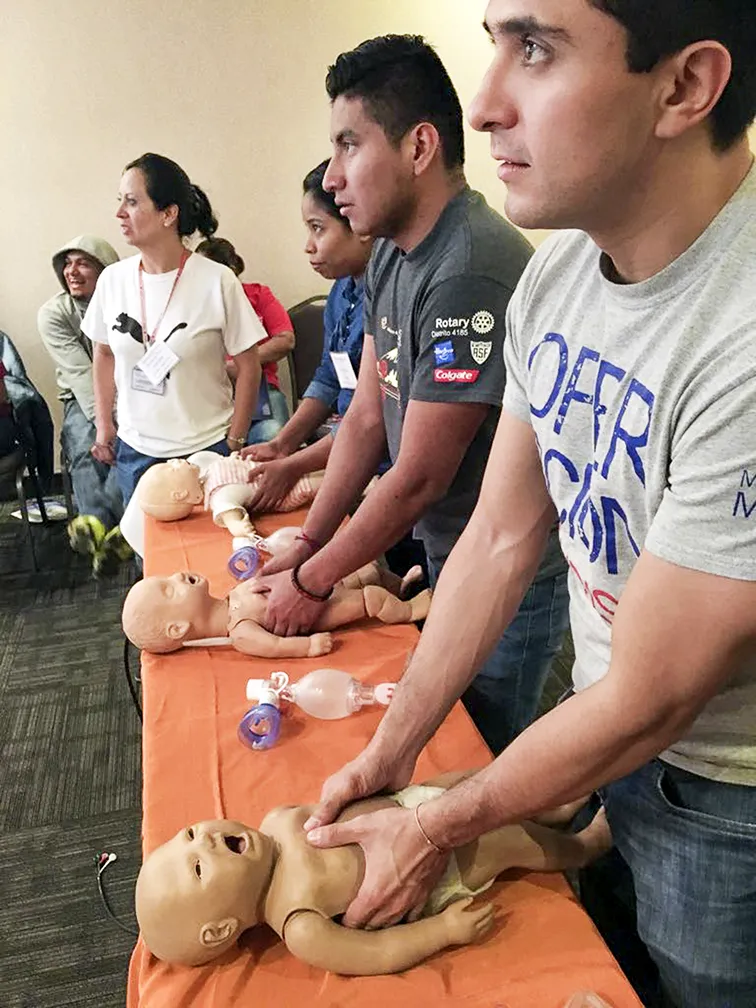 Operation Smile Mexico program coordinators Mauricio Rojas, right, and Bryan Mejia, center, practice delivering chest compressions to mannequins of infants during BLS training.