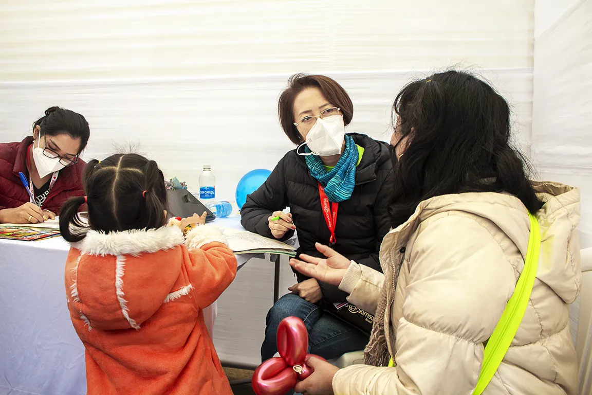 Midori Hanayama, speech-language pathologist of Brazil, consults a young patient and their caregiver during Operation Smile's June 2022 Women in Medicine surgical program in Lima, Peru.