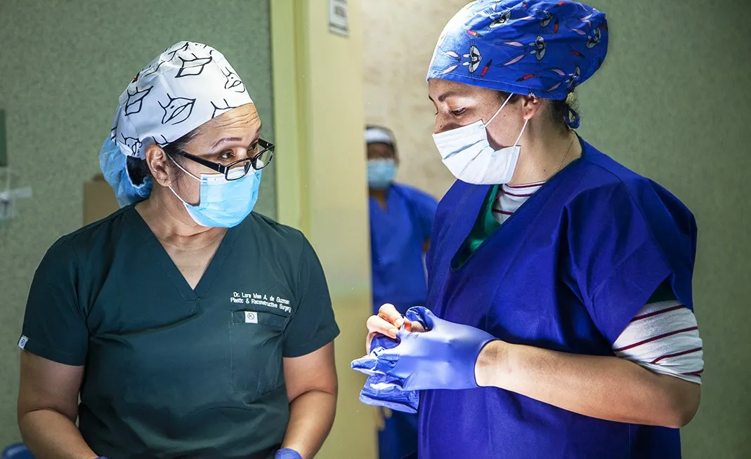 Dr. Lora Mae De Guzman, cleft surgeon from the Philippines, left, speaks with a fellow Operation Smile female volunteer during the Women in Medicine surgical program in Lima, Peru.