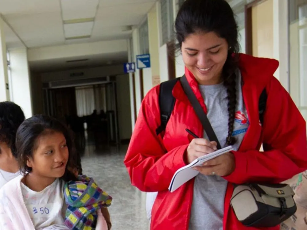 A student u-voicer takes notes while talking with a patient.